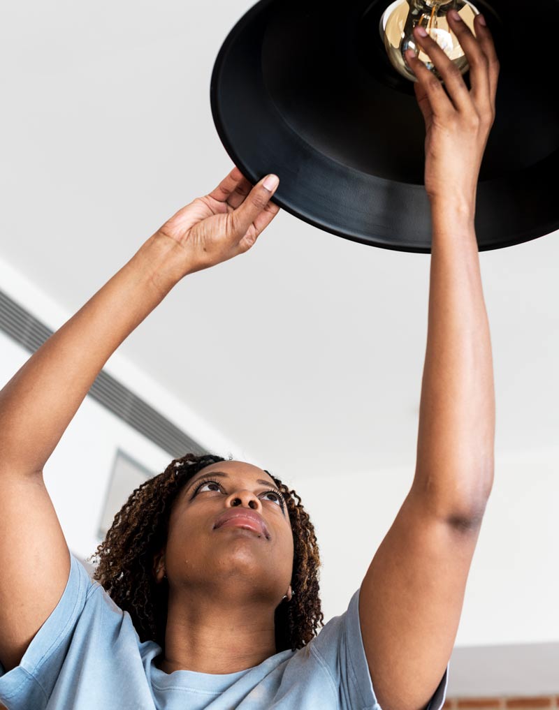 sustainability-woman-changing-lightbulb installing energy efficient lightbulbs